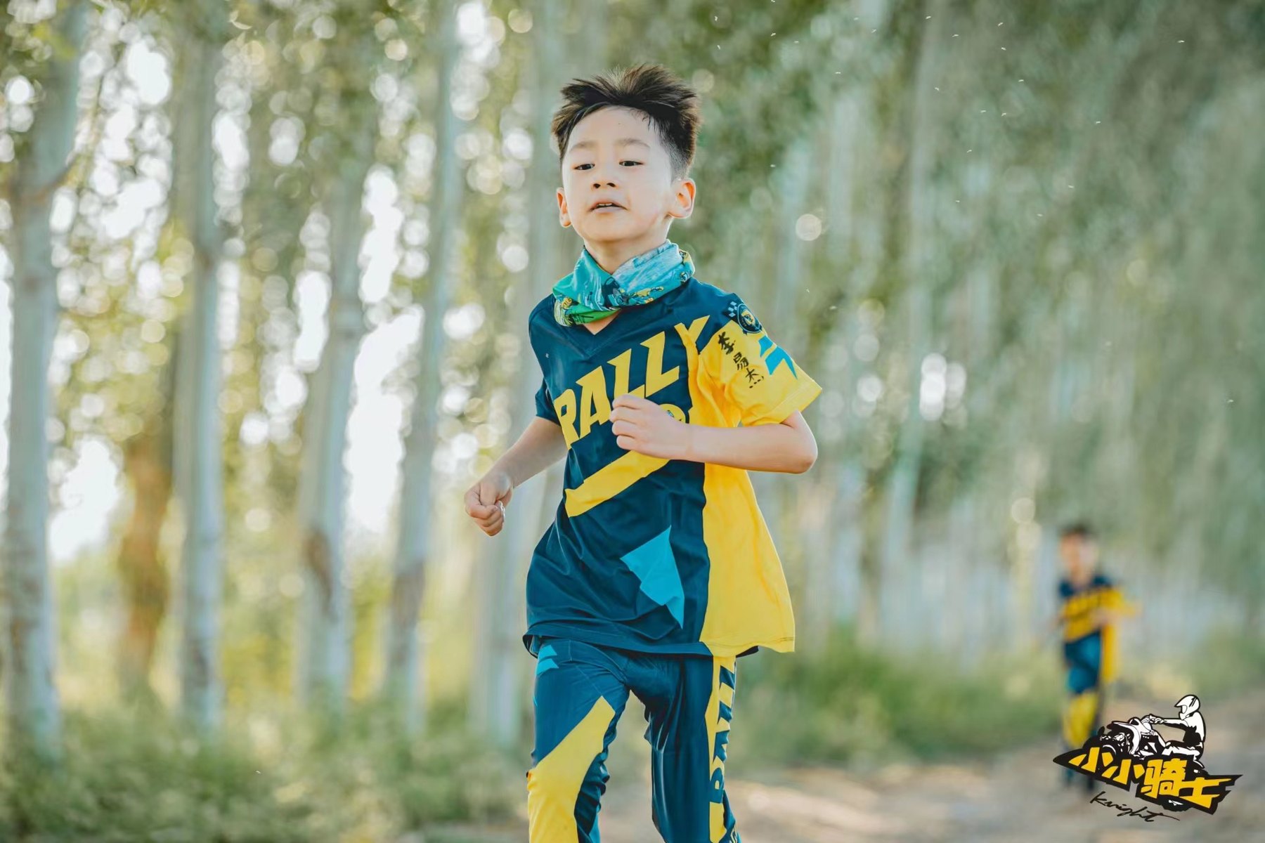 A young participant wearing Kids Rally Camp team clothing outdoors.